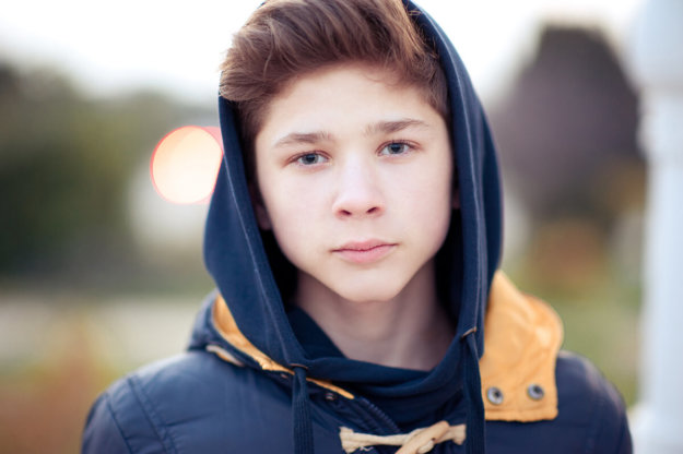 troubled teen stands outside with his hood up before looking for teen residential treatment centers